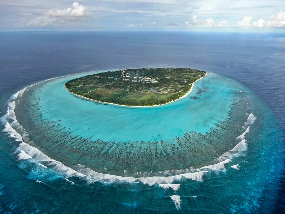 Aerial view of the whole island of Thoddoo and its surrounding turquoise reef